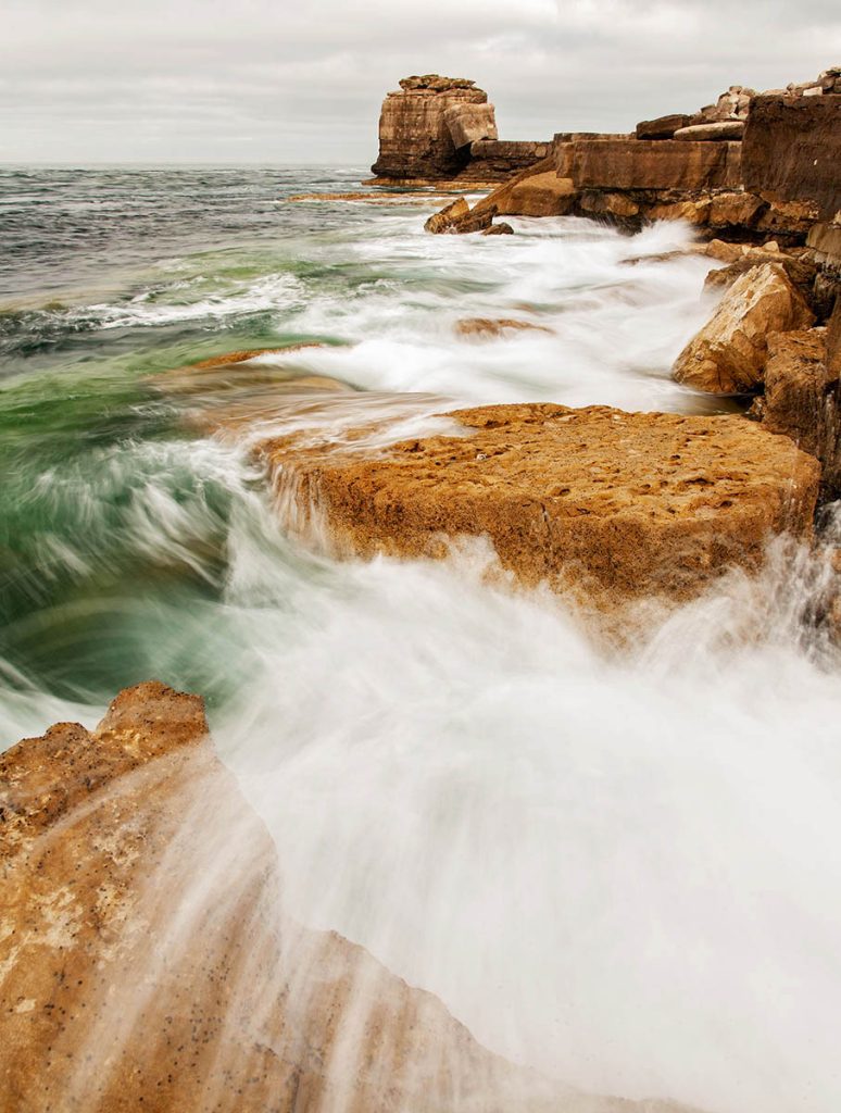 Waves crashing over Pulpit rock and the promontory at Portland Bill, near Weymouth, Jurassic Coast, Dorset, England. Pulpit Rock is an artificial stack that was left behind after quarrymen dug away a natural arch in 1870s. The Jurassic Coast is a stretch of coastline with a geology that dates back 185 million years, and is a UNESCO World Heritage Site.