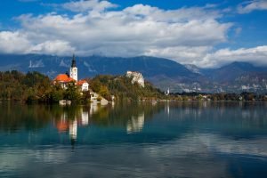 View across Lake Bled to the island church and clifftop castle in all it's autumn glory, Slovenia.