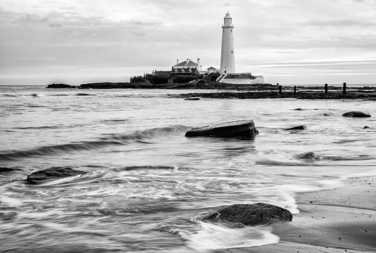 Black and white photo of Saint Mary's Lighthouse on Saint Mary's Island, situated north of Whitley Bay, Tyne and Wear, North East England. Seen at sunrise from the beach beside the causeway that runs out to the island. Whitley Bay is situated just north of Newcastle.
