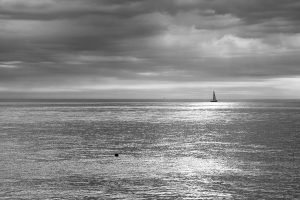 Beautiful light breaks through the clouds as a sailing boat passes by on an otherwise empty sea at Kingsdown, Kent, England.