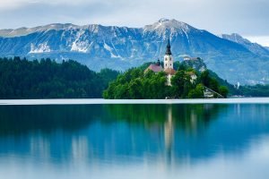 All in one view across to the beautiful island church of the assumption of Mary, Bled Castle and the Church of Saint Martin, all backed by Mount Stol and the Karavanke alps, Lake Bled, Slovenia.