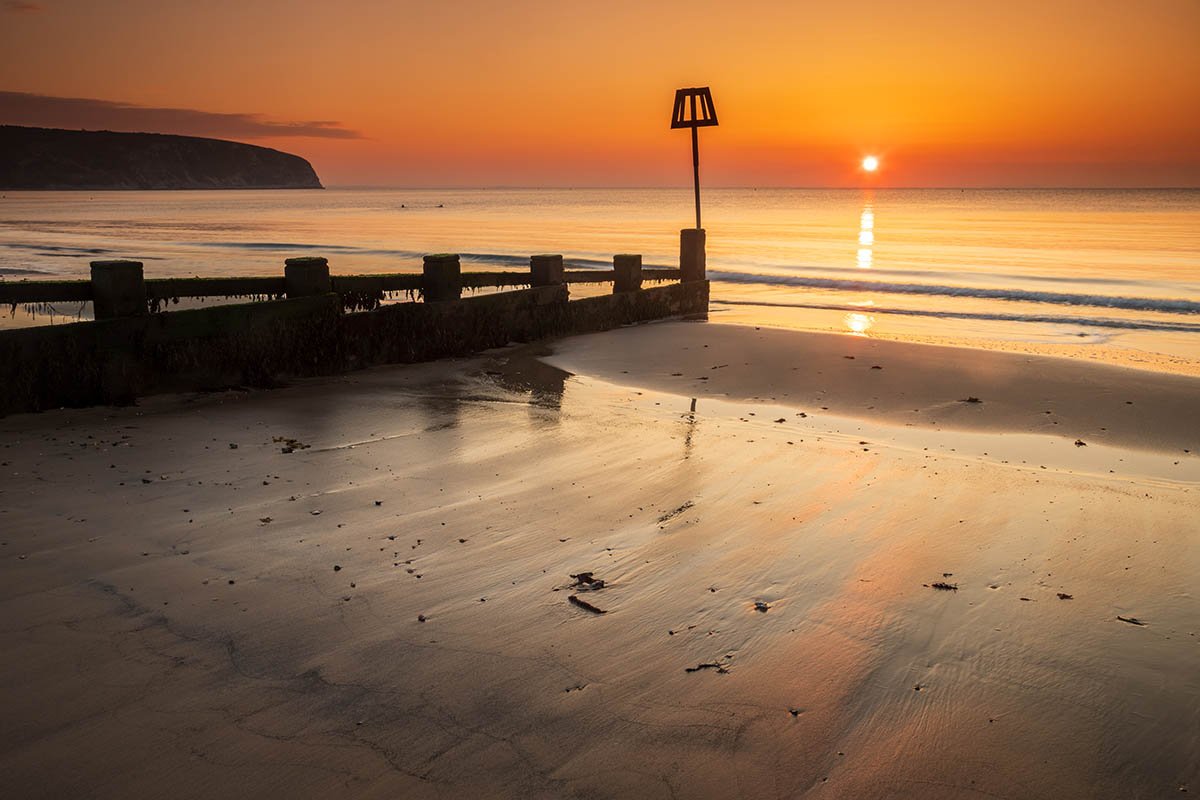 Sun rising Swanage Beach and Groyne, Dorset, England.