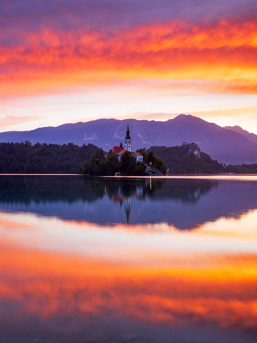 Sunrise at Lake Bled Castle and the island church of the assumption of Mary with the Karavanke mountains in the background, Slovenia.