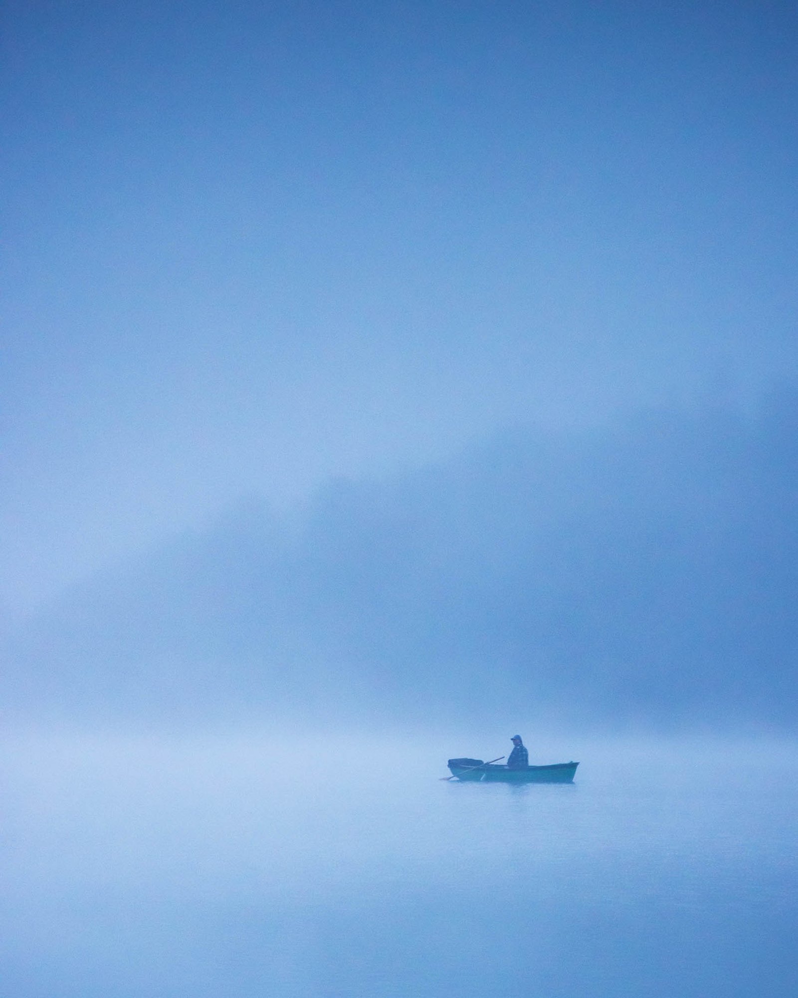 Man on boat in the morning mist at Lake Bohinj, Triglav National Park, Slovenia