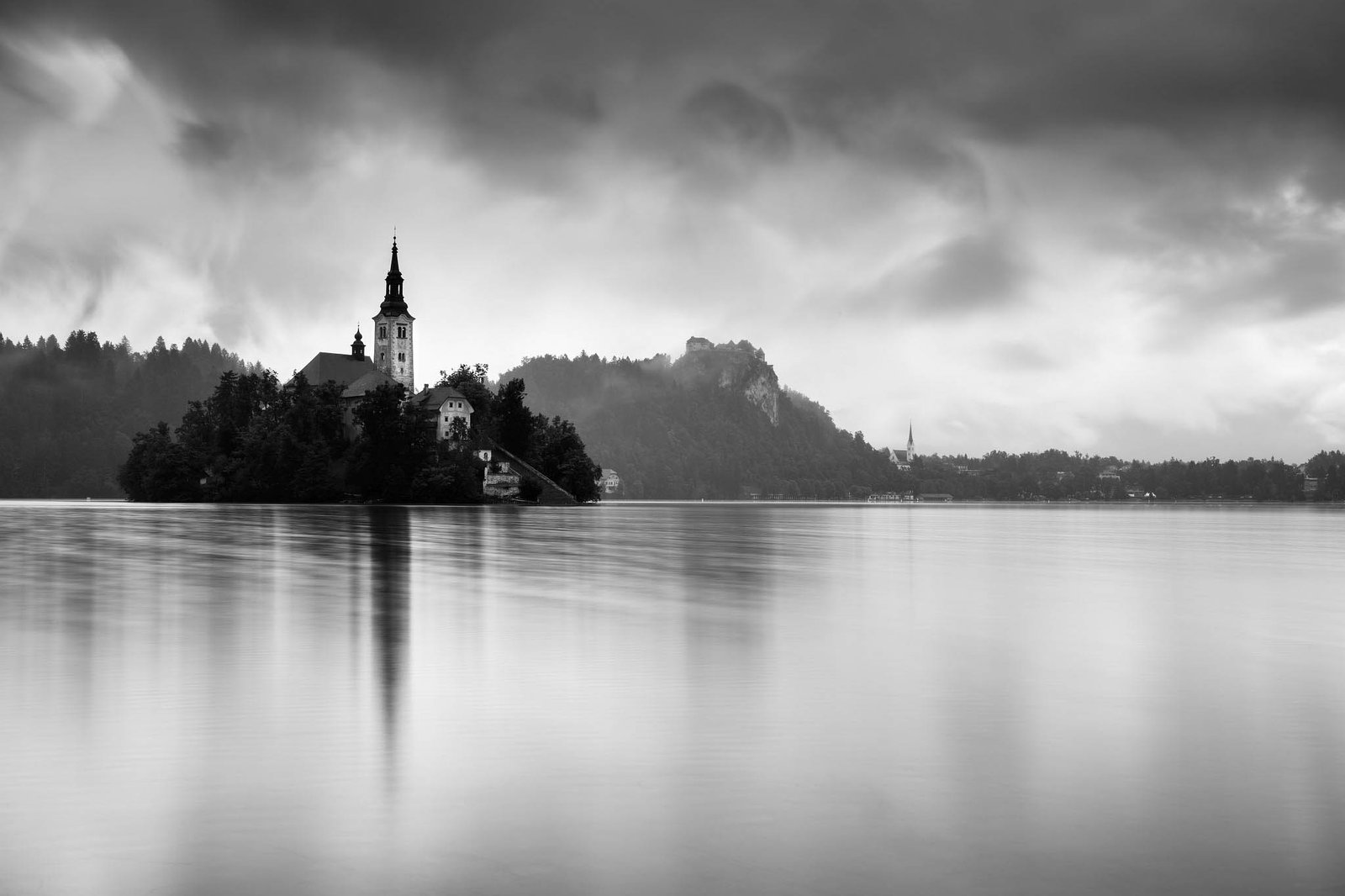Morning at Lake Bled's island church of the assumption of saint mary and hilltop castle after a night of heavy summer rain, Slovenia.