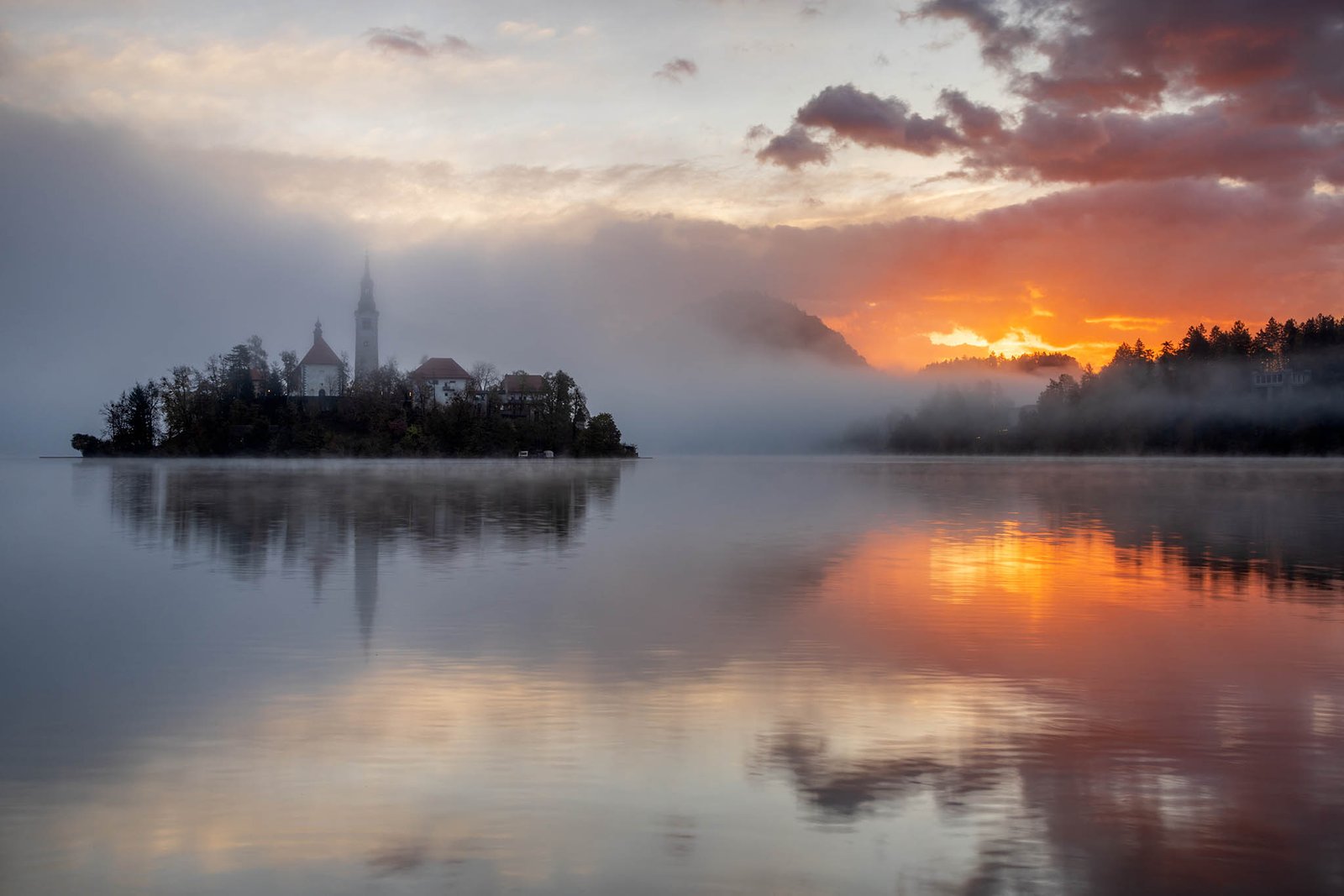 Sun rising over Lake Bled and the island church of the assumption of Mary, Slovenia.