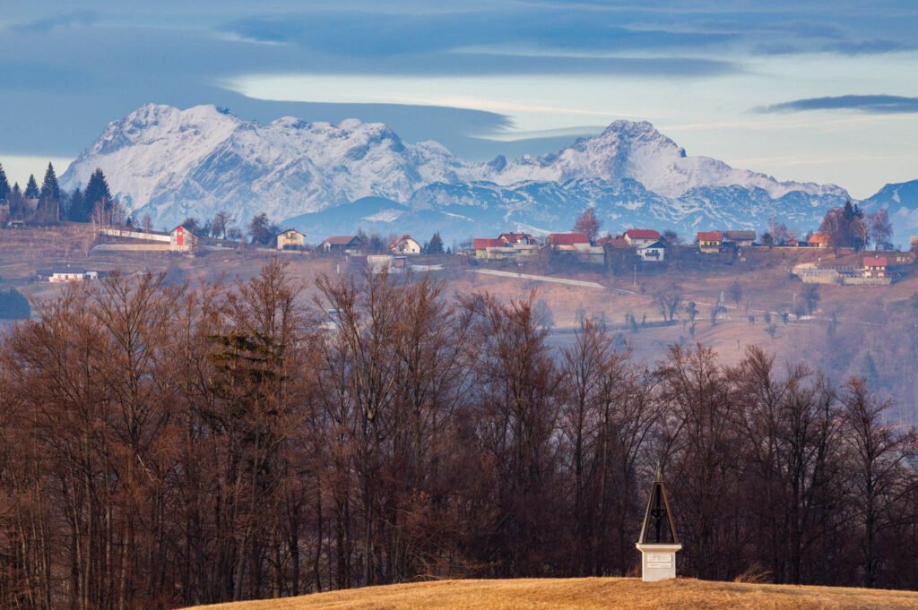 Evening view across a hill in prezganje to the east of Ljubljana, Slovenia. The shrine on the first hill is to Jesus Christ, built to commemorate the first visit of Pope John Paul the second to Slovenia in 1996 and the Kamnik Alps form the backdrop.