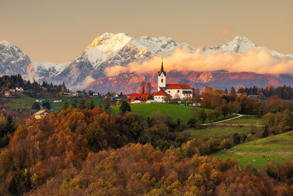 The church of Saint Margaret in Prezganje to the east of Ljubljana, Slovenia. The snow covered Kamnik Alps form a beautiful backdrop.